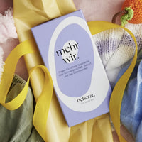 Spiel "Mehr Wir" von beherzt, papeterie, zeigt bunte Karten und Spielmaterialien auf einem Tisch.
