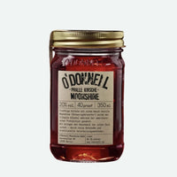 O’Donnel Moonshine Likör „Pralle Kirsche“ in einer Flasche, mit frischen Kirschen auf einem Holztablett.