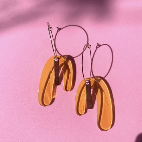 Klare orange Ohrringe von hej Ibiza by Ute Arnold, elegante Accessoires mit buntem Design, auf einem weißen Hintergrund.