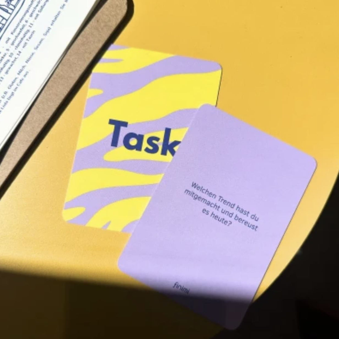 Buntes Ask & Task Spiel von Finimi, Papeterie, mit Karten und Anweisungen für kreative Aufgaben auf einem Tisch liegend