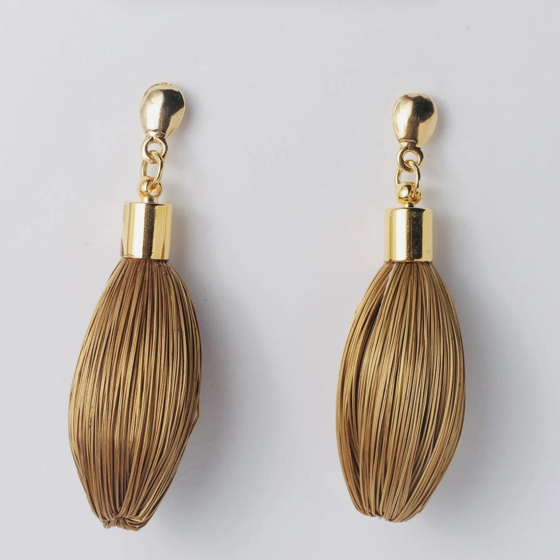 Goldene Ohrringe Buriti von Capido, elegantes Accessoire mit filigranen Details, sichtbar im Bild.